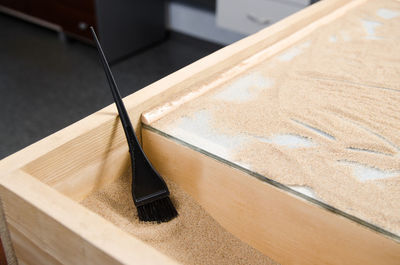 High angle view of brush with sand in container