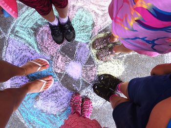 Low section of woman and kids standing over chalk drawing on street