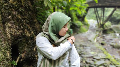 Side view of young woman standing in forest