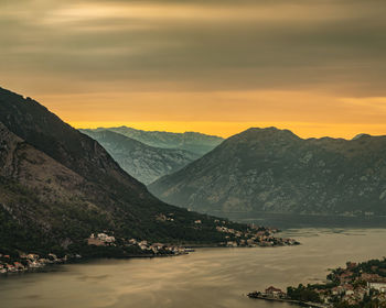 Scenic view of river by mountains against sky during sunset