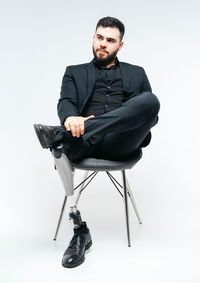 Young man sitting on chair against white background