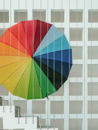 Close-up of multi colored umbrella against square concrete block wall