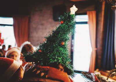 Close-up of child wearing christmas tree hat at home