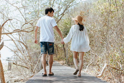 Rear view of couple walking along plants