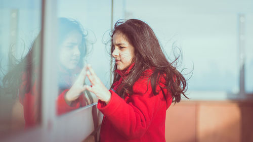 Side view of girl standing by window on boat