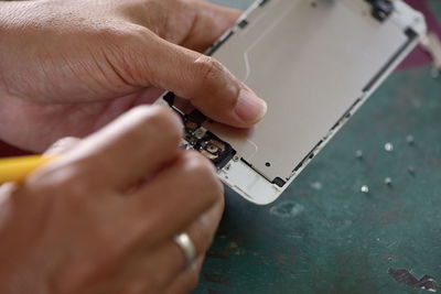 Cropped hands of person repairing mobile phone on table