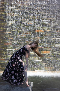 Side view of woman with arms raised in city