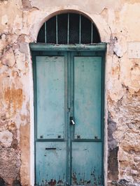 Entrance door, old house, weathered stone wall and weathered blue door closed 