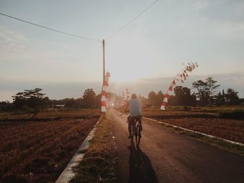 Rear view of man riding bicycle on road