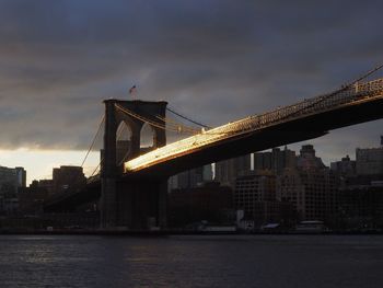Golden gate bridge over river against sky in city at dusk