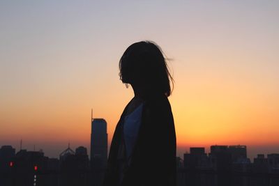 Silhouette of woman in city at sunset