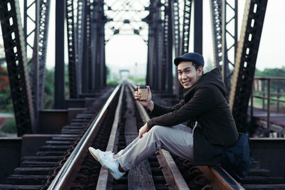 Side view of smiling man sitting on mobile phone