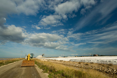 Road amidst field against sky