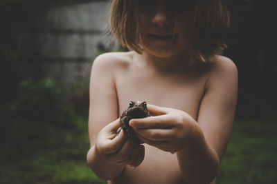 Midsection of shirtless woman holding outdoors