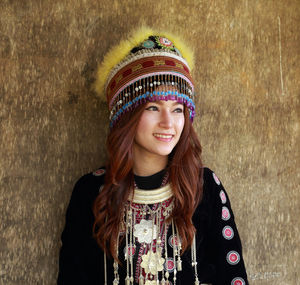 Smiling woman in traditional clothing standing against wall