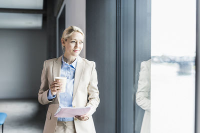 Businesswoman with coffee and documents at the window