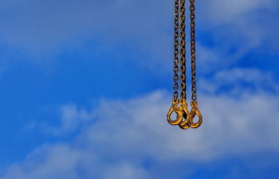 Low angle view of hooks against blue sky