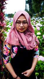 Portrait of young woman with pink hair standing against plants