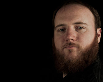 Close-up portrait of young man against black background