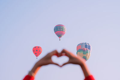 Low angle view of hot air balloons flying against sky