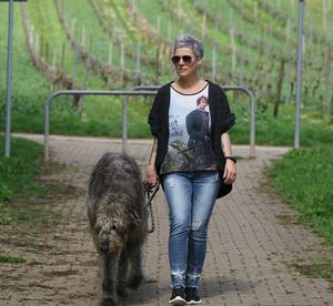 Full length of woman standing with dog on footpath