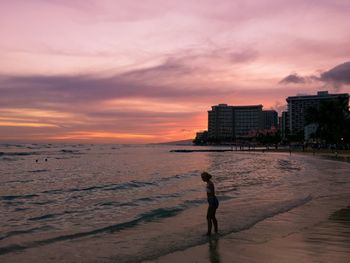 Man standing on beach against sky during sunset