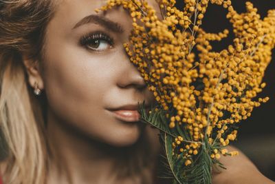 Close-up portrait of smiling woman with yellow flowers 