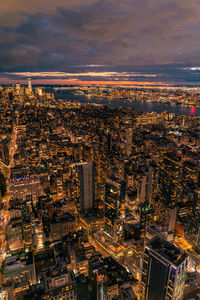 Aerial view of illuminated skyscraper buildings in city at night at high angle