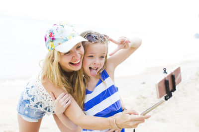 Portrait of happy girl holding camera on beach