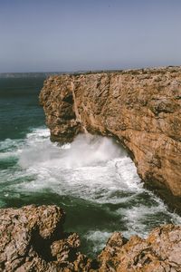 Scenic view of rocks in sea against clear sky