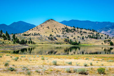 Scenic view of lake and mountains against blue sky