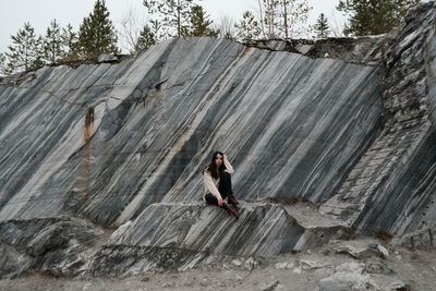 Woman standing on rock against trees