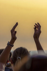 Close-up of woman arms raised against clear sky during sunset