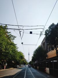 Road by trees against sky in berlin with tv tower in the back