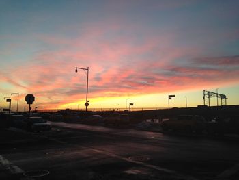 Cars on road against dramatic sky during sunset