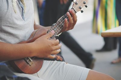 Midsection of man playing ukulele