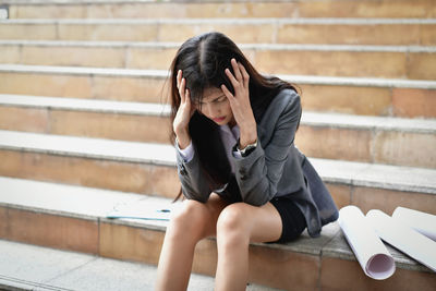 Worried businesswoman with head in hands sitting on steps