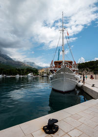 Sailboats moored at harbor against sky