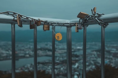 Close-up of padlocks on chain over railing against sky