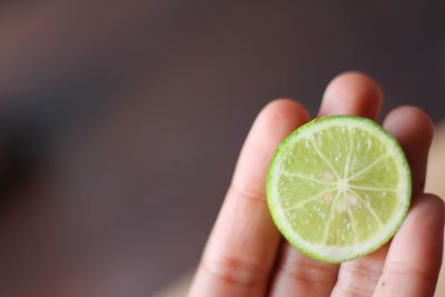 Close-up of hand holding apple against white background