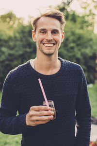 Portrait of happy man holding elderflower drink on roof garden