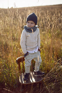 Fashionable boy child stand on a chair in autumn on the field