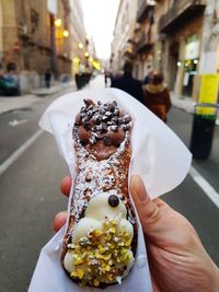 Midsection of person holding ice cream on street