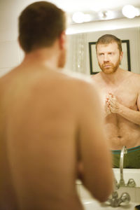 Rear view of shirtless man standing in bathroom