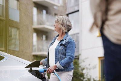 Senior woman charging electric car