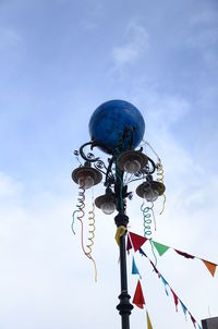 Low angle view of street light and decoration against sky