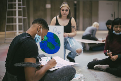 Male and female activist preparing poster during covid-19