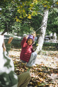 Playful girl hanging on rope while playing at park