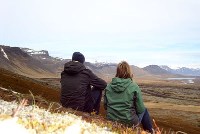 Rear view of woman sitting on mountain