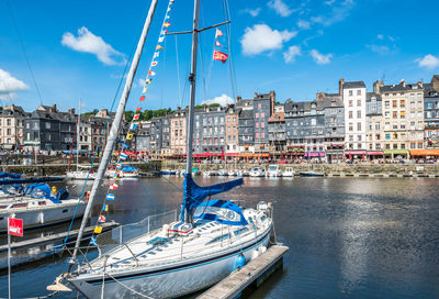 Boats moored at harbor against buildings in city